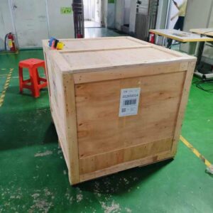 Large wooden shipping crate in a workshop, with a barcode label on the side.
